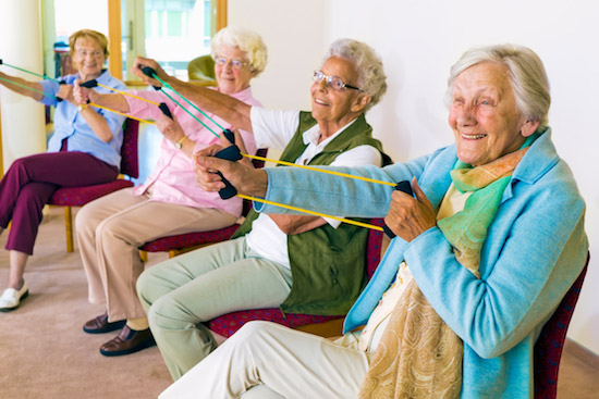 senior assisted living housing group doing exercise with therabands