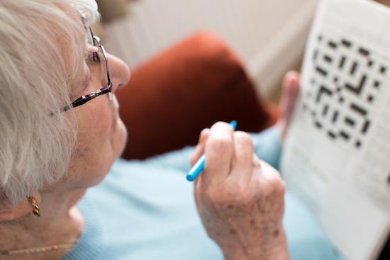senior memory care facility with woman doing crossword puzzle
